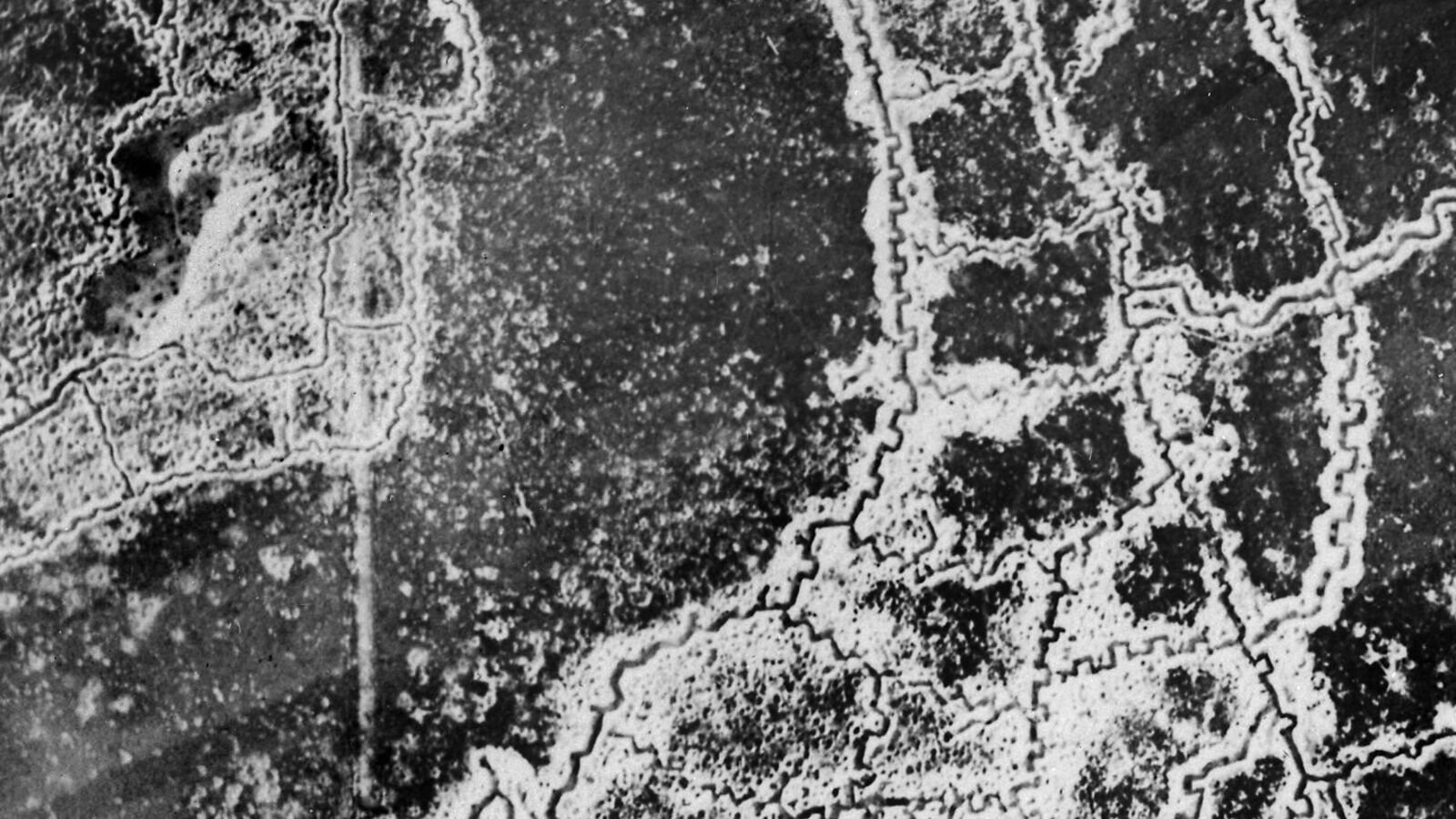 A black and white aerial reconnaissance photograph showing two systems of zigzagging trenches separated by a strip of shell-cratered open ground.