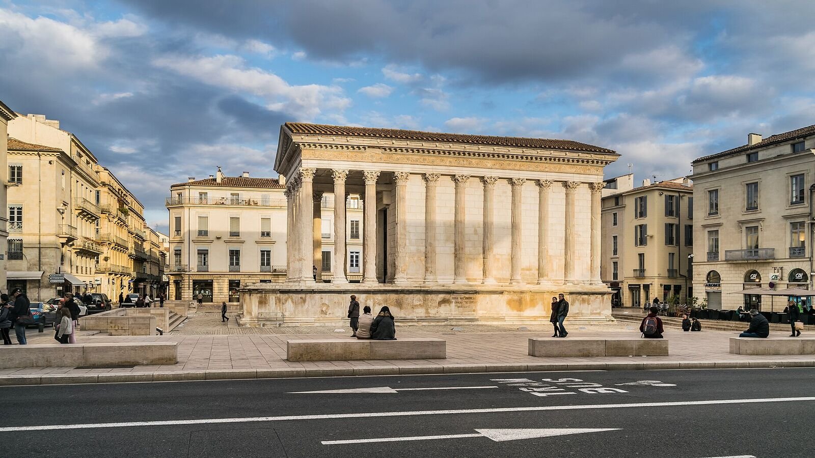 The Maison Carree at Nimes, a rectangular Roman temple with tall Corinthian columns across its front porch, raised on a high stone platform with a single flight of steps.